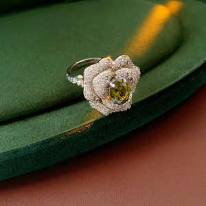 Macro shot of silver flower ring with olive green gemstone and white zircon petals