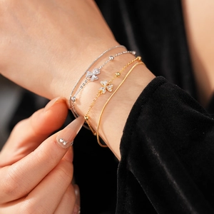 Nahaufnahme eines vierteiligen Armband-Sets in Gold und Silber mit Blumenanhängern