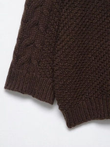 Detail of dark brown chunky cable knit sweater showing textured weave and ribbed cuffs