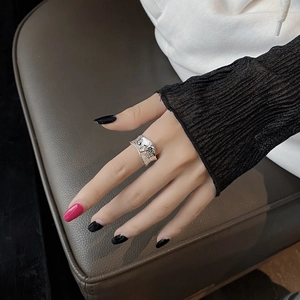 Close-up of silver ring with hammered texture and irregular edges on model's finger