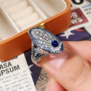 Primer plano de anillo cóctel vintage con zafiro azul y grabado calado en plata pura