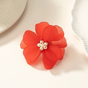 Close-up of frosted red acrylic flower ring with center pearls on a ceramic dish