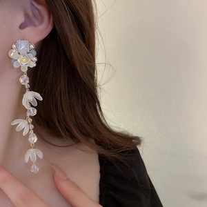 Close-up of elegant flower tassel earrings with blue gemstones worn by a model