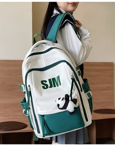 Side view of large green and white vintage backpack with panda charm and SJM logo