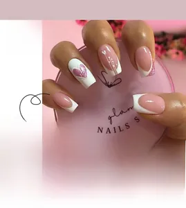 Detail of pink French press-on nails with heart patterns and glitter accents
