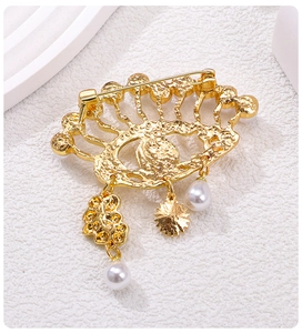 Detailed back view of gold hollow wave brooch with safety pin and pearl charms