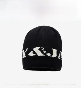 Detail view of black knit beanie featuring white jacquard letter pattern and tight texture