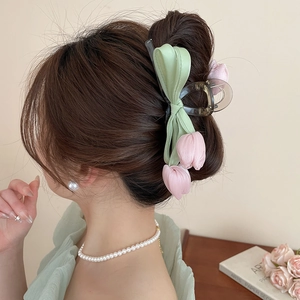 Detail of a pink tulip hair claw with soft green ribbon on a model in a French style