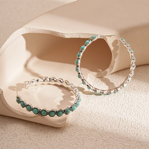 Vintage round hoop earrings with turquoise stones on artistic beige pedestal