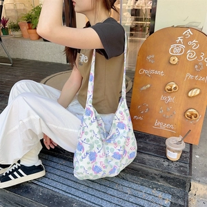 Floral canvas hobo bag with wide strap shown in a casual outdoor cafe setting