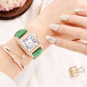 Close-up of elegant square quartz watch with green leather strap and gold bracelets