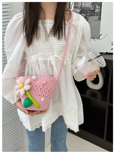 Detail of a pink knitted crossbody bag with a large floral embellishment and pearl beads