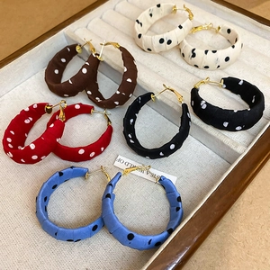 Close-up of polka dot fabric-wrapped hoop earrings in beige, brown, red, and blue colors