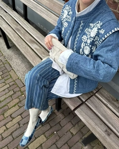 Outdoor street shot of a blue denim quilted jacket with white floral embroidery detail