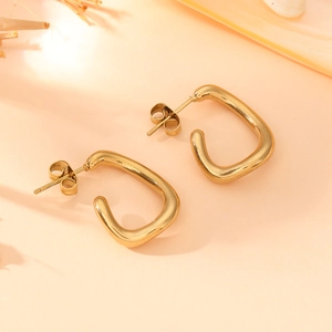 Polished gold stainless steel square hoop earrings on a soft pink decorative base