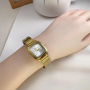 Close-up of elegant gold square quartz watch for women with metal chain strap on a wrist
