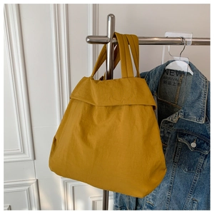 Detail of a large mustard yellow nylon tote bag hanging on a display stand