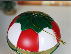 Detail of a red and white striped Christmas ball ornament with green leaf and gold string