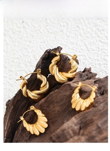 Macro shot of gold twisted hoop earrings with ribbed texture on wooden display