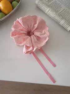 Detailed view of pink lace scrunchie with long ribbons on a decorative background