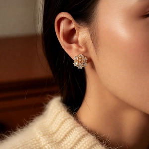 Close-up of 14k gold plated flower stud earring with shimmering crystals on model