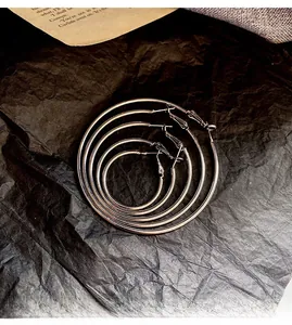 Set of 5 large silver hoop earrings in sizes 3cm to 7cm on a vintage background