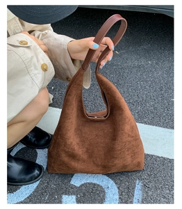 Brown suede tote bag shown in a lifestyle scene with a flexible soft material texture