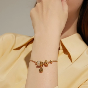 Close-up of golden zircon heart charm bracelet on wrist with elegant snake chain details