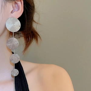 Close-up of silver textured tiered drop earrings showing cascading circular metal plates