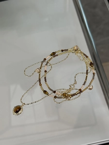 Detailed macro view of gold plated multi-layer necklace with tiger eye stone pendant