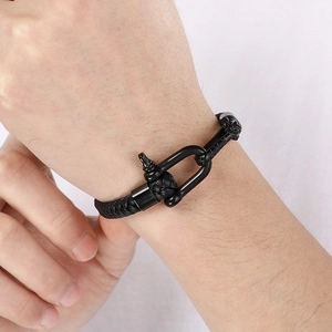 Macro shot of men's braided leather bracelet with black matte horseshoe clasp detail