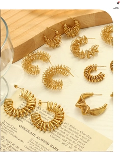 Mise en scène artistique de boucles d'oreilles dorées en C sur supports vintage