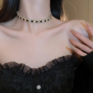 Gros plan d'un collier choker doré serti de cristaux noirs et transparents