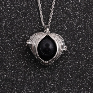 Silver heart wing pendant necklace with blue sandstone sphere on black background