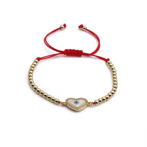 Red braided cord bracelet with gold beads and a heart-shaped evil eye pendant