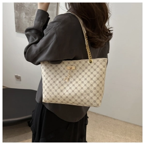 Close-up of beige tote bag featuring geometric patterns and a golden deer charm detail