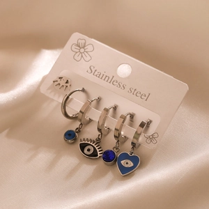Detail of silver stainless steel earrings set with blue eye and heart charms on silk