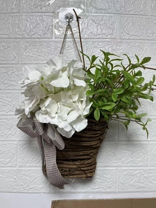 Detail of white hydrangea arrangement in brown woven basket with a gray polka dot bow