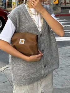 Gilet in maglia grigia con bottoni da donna abbinato a una borsa a tracolla alla moda