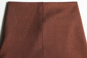 Gros plan sur le tissu côtelé marron et les détails de couture de cette robe longue