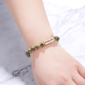 Detail of beaded bracelet with natural stone and rose gold plate engraved with Her King