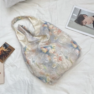 Detail of floral lace tote bag featuring blue and orange blossoms with 3D feather textures