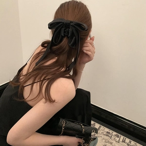 Detailed view of an elegant black satin bow hair claw clip worn on a woman's hair