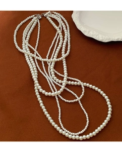 Detail of multi-layer glass pearl necklace with vintage silver clasp on brown fabric
