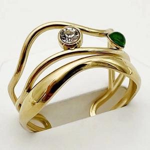 Detailed macro view of wavy gold-plated steel ring with green and clear zircon gemstones