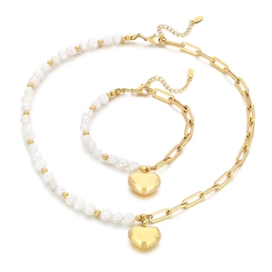 Ensemble collier et bracelet en acier doré avec perles et pendentif cœur sur fond blanc