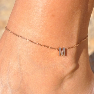 Personalized rose gold stainless steel anklet with capital letter M charm on ankle.