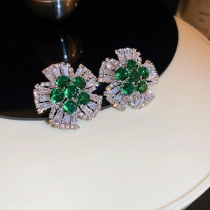Macro shot of silver flower drop earrings with green emerald gems and clear zircons