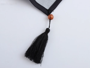Close-up of black fringe tassel and orange bead detail on vintage printed blouse