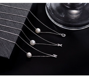 Macro shot of S925 silver pearl necklaces featuring sparkling rhinestone letter pendants